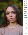 Beautiful young woman with long straight hair looking at camera in autumn park 137671729