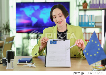 Woman in a bright jacket presenting a European Union document in a modern office setting during the daytime 137671799