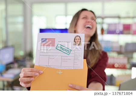 Woman joyfully holds approved visa application in modern office environment with a sense of accomplishment Woman joyfully holds approved visa application in modern office environment with a sense of accomplishment 137671804