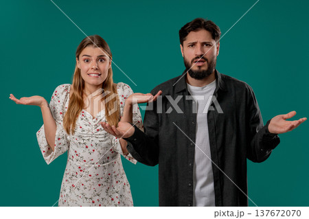 Confused Young Couple Shrugging Shoulders In Uncertainty While Looking At Camera Confused Young Couple Shrugging Shoulders In Uncertainty While Looking At Camera 137672070