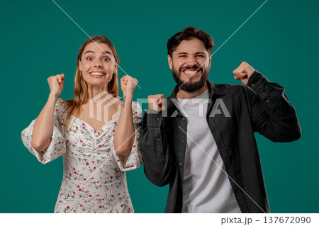Lucky man and woman cheerfully raise fists in victory, luck while smiling 137672090