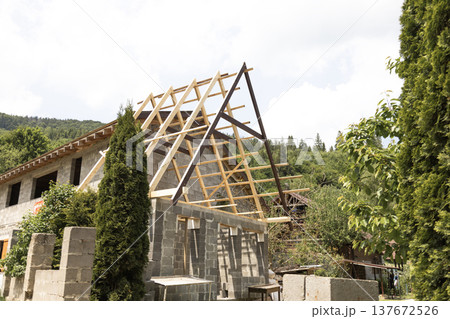 Timber framework extension built next to mountain house representing construction process 137672526