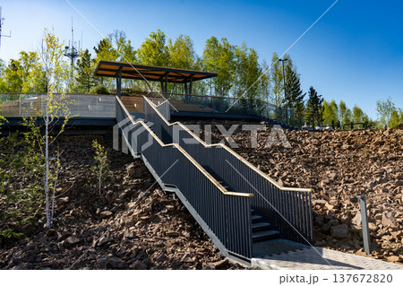 Modern Outdoor Staircase Leading to Observation Deck on Rocky Hillside With Trees and Blue Sky Modern Outdoor Staircase Leading to Observation Deck on Rocky Hillside With Trees and Blue Sky 137672820