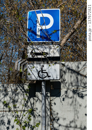 Accessible Parking Signs With Wheelchair Symbol and Blue P Surrounded by Trees and Shadows Accessible Parking Signs With Wheelchair Symbol and Blue P Surrounded by Trees and Shadows 137672821