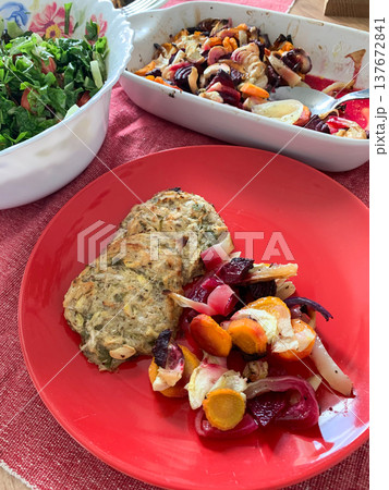A plate holds zucchini pancakes alongside baked vegetables and a fresh green salad. This healthy breakfast offers gluten-free options for anyone looking for nutritious meals A plate holds zucchini pancakes alongside baked vegetables and a fresh green salad. This healthy breakfast offers gluten-free options for anyone looking for nutritious meals 137672841