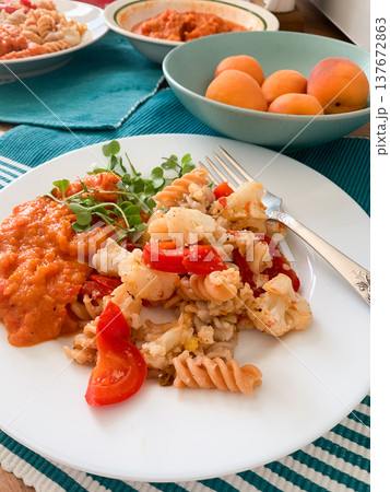 A healthy breakfast is prepared with gluten-free pasta, baked cauliflower, sweet pepper, and zucchini caviar. Fresh apricots provide a simple dessert on a sunny morning in a kitchen A healthy breakfast is prepared with gluten-free pasta, baked cauliflower, sweet pepper, and zucchini caviar. Fresh apricots provide a simple dessert on a sunny morning in a kitchen 137672863