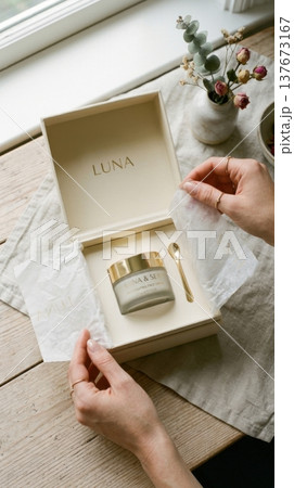 Hands Lifting Delicate Tissue Paper in Luxury Box Reveal 137673167
