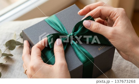 Manicured Hands Untying Silk Ribbon on Premium Gift Box 137673268