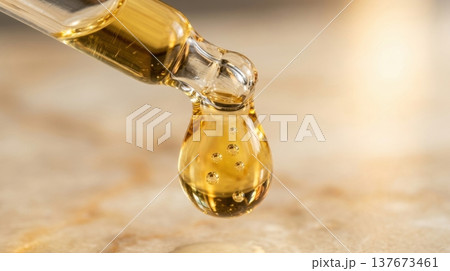 Golden Argan Hair Oil Drop from Glass Pipette Macro Shot Golden Argan Hair Oil Drop from Glass Pipette Macro Shot 137673461