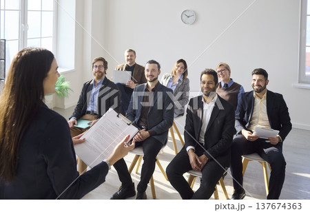 Smiling business team listening to coach during office training seminar session Smiling business team listening to coach during office training seminar session 137674363