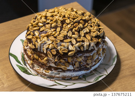 A multi layered cake covered in chocolate icing and topped with a large amount of roasted peanuts A multi layered cake covered in chocolate icing and topped with a large amount of roasted peanuts 137675211