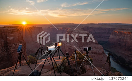 Smartphones and cameras on tripods on the edge of a viewing platform in a picturesque canyon during sunrise. Conceptual ideas for travel blogging, outdoor photography, and influencer culture. Smartphones and cameras on tripods on the edge of a viewing platform in a picturesque canyon during sunrise. Conceptual ideas for travel blogging, outdoor photography, and influencer culture. 137675244
