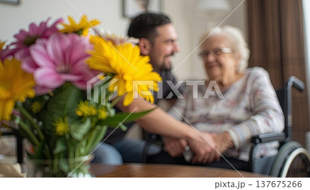 A daughter wishes her wheelchair-bound mother a Happy Mother's Day. An elderly woman in a wheelchair at home. Conceptual themes of healthcare, aging, home care, and Mother's Day greetings. 137675266