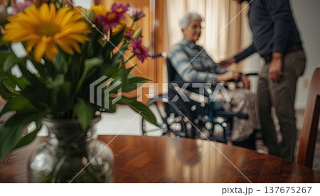 A daughter wishes her wheelchair-bound mother a Happy Mother's Day. An elderly woman in a wheelchair at home. Conceptual themes of healthcare, aging, home care, and Mother's Day greetings. 137675267