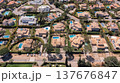 Aerial view shows many houses with swimming pools surrounded by trees and roads in a residential area on a sunny day. People enjoy outdoor activities 137676847