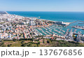 Vilamoura marina in Portugal features many boats docked at the harbor with views of the ocean and city on a sunny day. Tourists enjoy the vibrant atmosphere Aerial 137676856