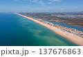 View of Ria Formosa and Praia de Faro taken from a drone. The coastline features sand and water, with nearby buildings and greenery visible 137676863