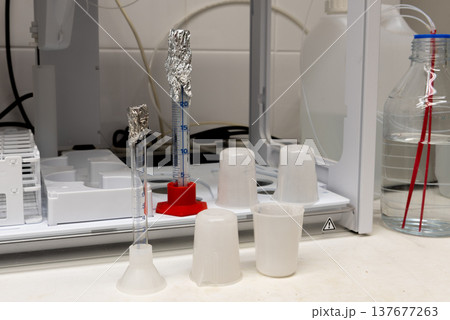Laboratory equipment. Plastic beakers, glass measuring cylinders and autosampler Laboratory equipment. Plastic beakers, glass measuring cylinders and autosampler 137677263