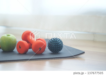 Small weights and fruit on exercise mat in living room Small weights and fruit on exercise mat in living room 137677505