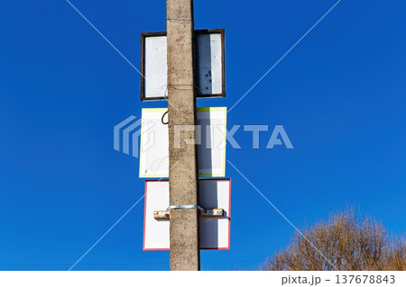 Concrete utility pole with blank sign backs attached against vivid deep blue sky, rustic texture, bright daylight Concrete utility pole with blank sign backs attached against vivid deep blue sky, rustic texture, bright daylight 137678843