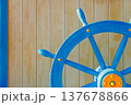 Close-up of blue wooden ship steering wheel mounted on a light wooden wall background. Nautical themed decoration with copy space, symbol of navigation, leadership, travel and maritime adventure 137678866