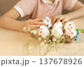 Child decorating Easter eggs with hand drawn doodle patterns 137678926