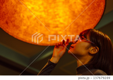 オレンジ色の光を見つめる女性の横顔 オレンジ色の光を見つめる女性の横顔 137679289