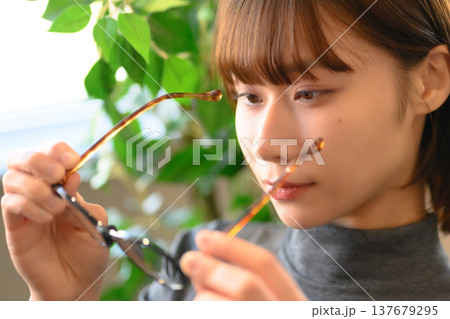 眼鏡のつるを触る女性の顔の接写 眼鏡のつるを触る女性の顔の接写 137679295