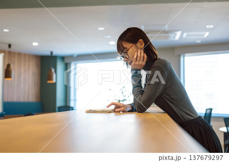 カフェでタブレットを見る眼鏡の女性 137679297