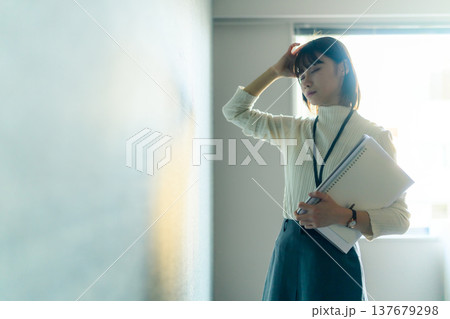 疲労で頭を抱える女性社員 （シネマティックフォト） 137679298