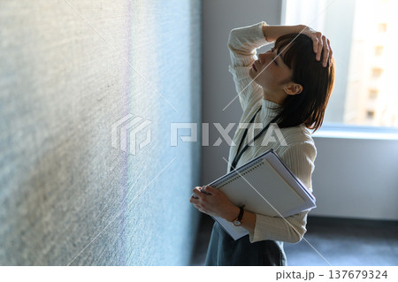 壁に寄りかかり頭を抱える女性 （シネマティックフォト） 137679324