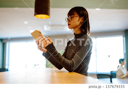 明るい窓際で資料を読む女性 137679335