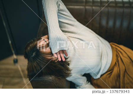 ソファで疲れてうずくまる女性 ソファで疲れてうずくまる女性 137679343