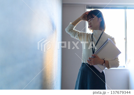 書類を持ち頭を抱える女性社員 （シネマティックフォト） 137679344