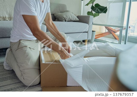 Man unpacking cardboard box with new furniture delivery Man unpacking cardboard box with new furniture delivery 137679357