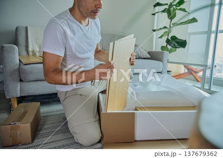 Man assembling flat-pack furniture in living room 137679362