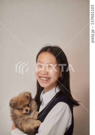 家のリビングで子犬と遊んでいる女子中学生の姿 家のリビングで子犬と遊んでいる女子中学生の姿 137681105