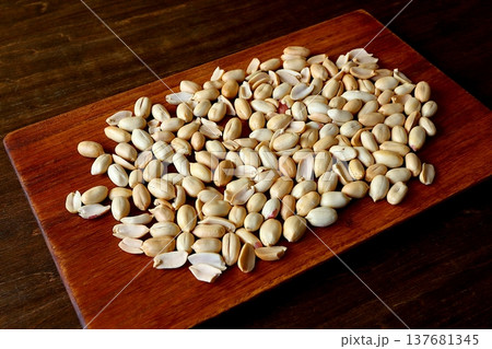 テーブル背景のカッティングボードに盛られたピーナッツ 137681345