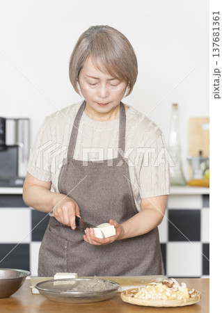 キッチンで野菜を切り料理の下ごしらえをするシニア女性 137681361