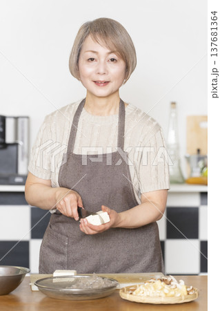 キッチンで野菜を切り料理の下ごしらえをするシニア女性 137681364