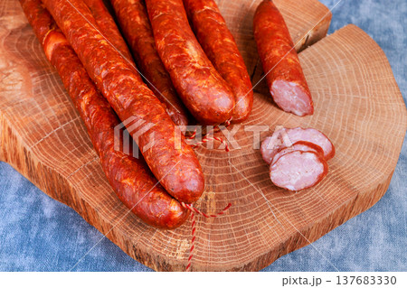 Freshly made sausages displayed on wooden board in kitchen setting Freshly made sausages displayed on wooden board in kitchen setting 137683330
