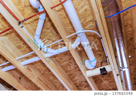 Pipes ducts installed under wooden ceiling in construction site for building project Pipes ducts installed under wooden ceiling in construction site for building project 137683349