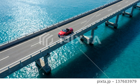 海上の橋を駆け抜けるスポーツカーと太陽に輝く水面の風景 137683979