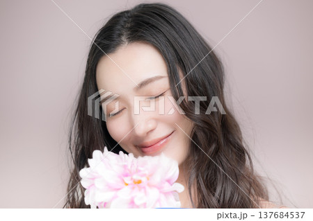 ダリアの花を持って多幸感にあふれるピンクの春色イメージの女性の美容ビューティーイメージ 137684537