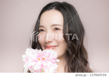 ダリアの花を持って多幸感にあふれるピンクの春色イメージの女性の美容ビューティーイメージ 137684539