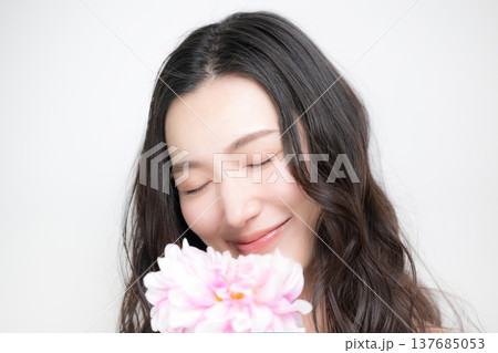 ダリアの花を持って多幸感にあふれるピンクの春色イメージの女性の美容ビューティーイメージ 137685053