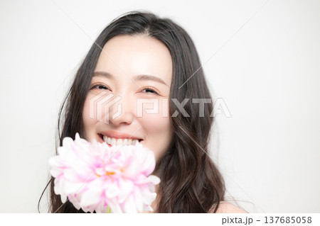 ダリアの花を持って多幸感にあふれるピンクの春色イメージの女性の美容ビューティーイメージ 137685058