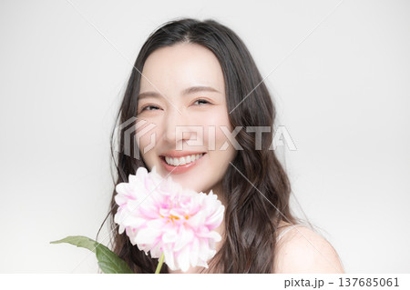 ダリアの花を持って多幸感にあふれるピンクの春色イメージの女性の美容ビューティーイメージ 137685061