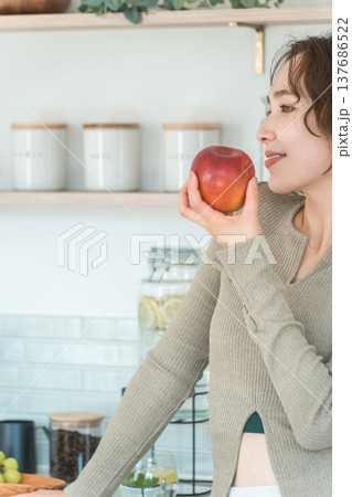 自宅のキッチンでりんごを食べる女性(ダイエット,ベジタリアン) 137686522