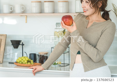 自宅のキッチンでりんごを食べる女性(ダイエット,ベジタリアン) 137686523